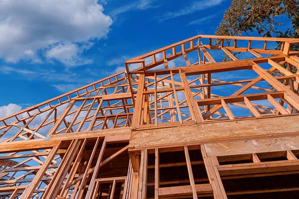 Wooden roof trusses on a new construction home against a blue Texas sky